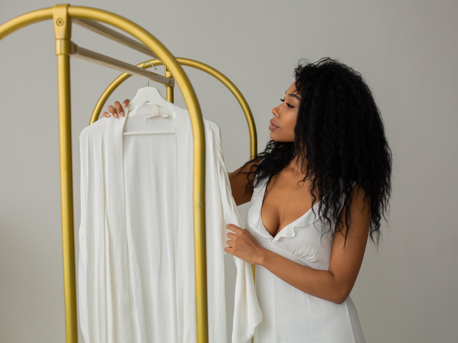 A woman holding up a white shirt on top of a rack.