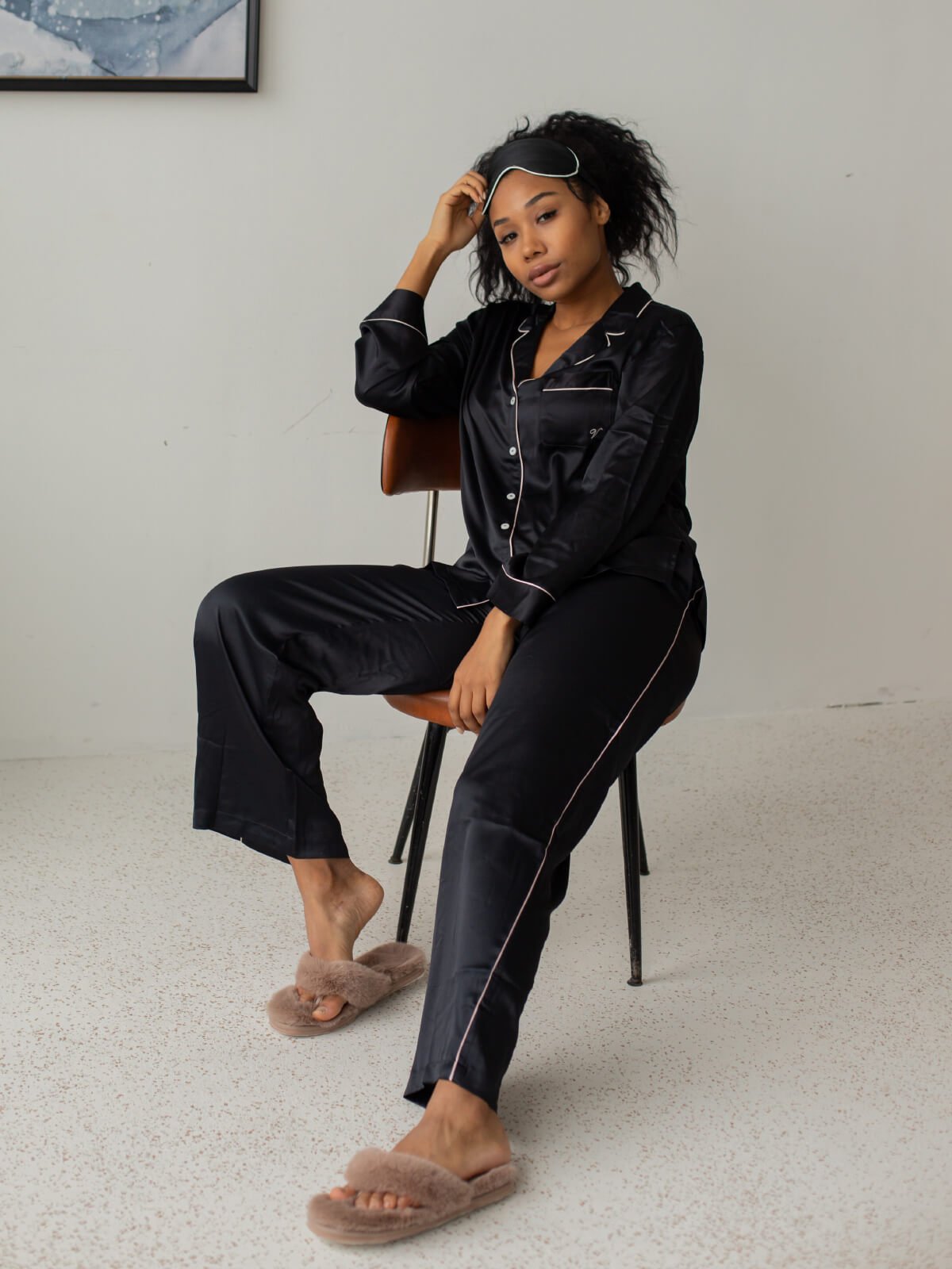 A woman sitting on top of a chair wearing black pajamas.