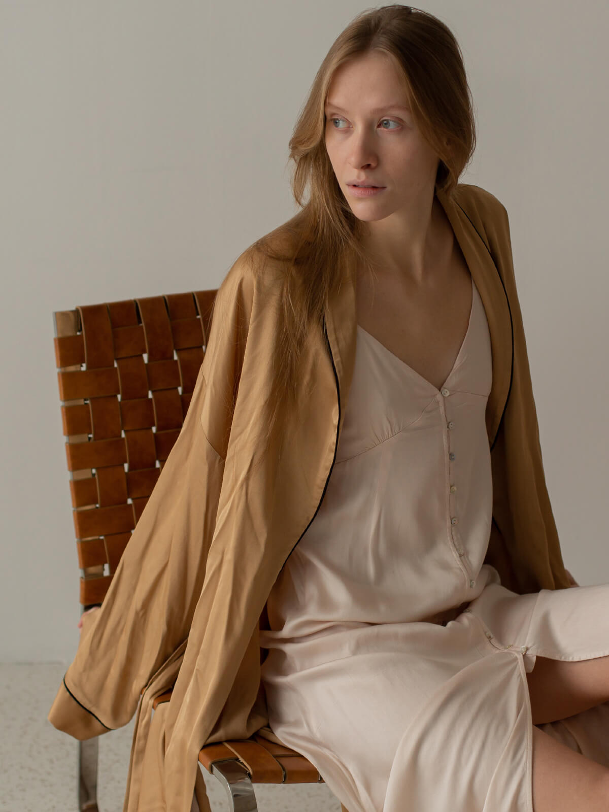 A woman sitting on top of a chair wearing a brown jacket.