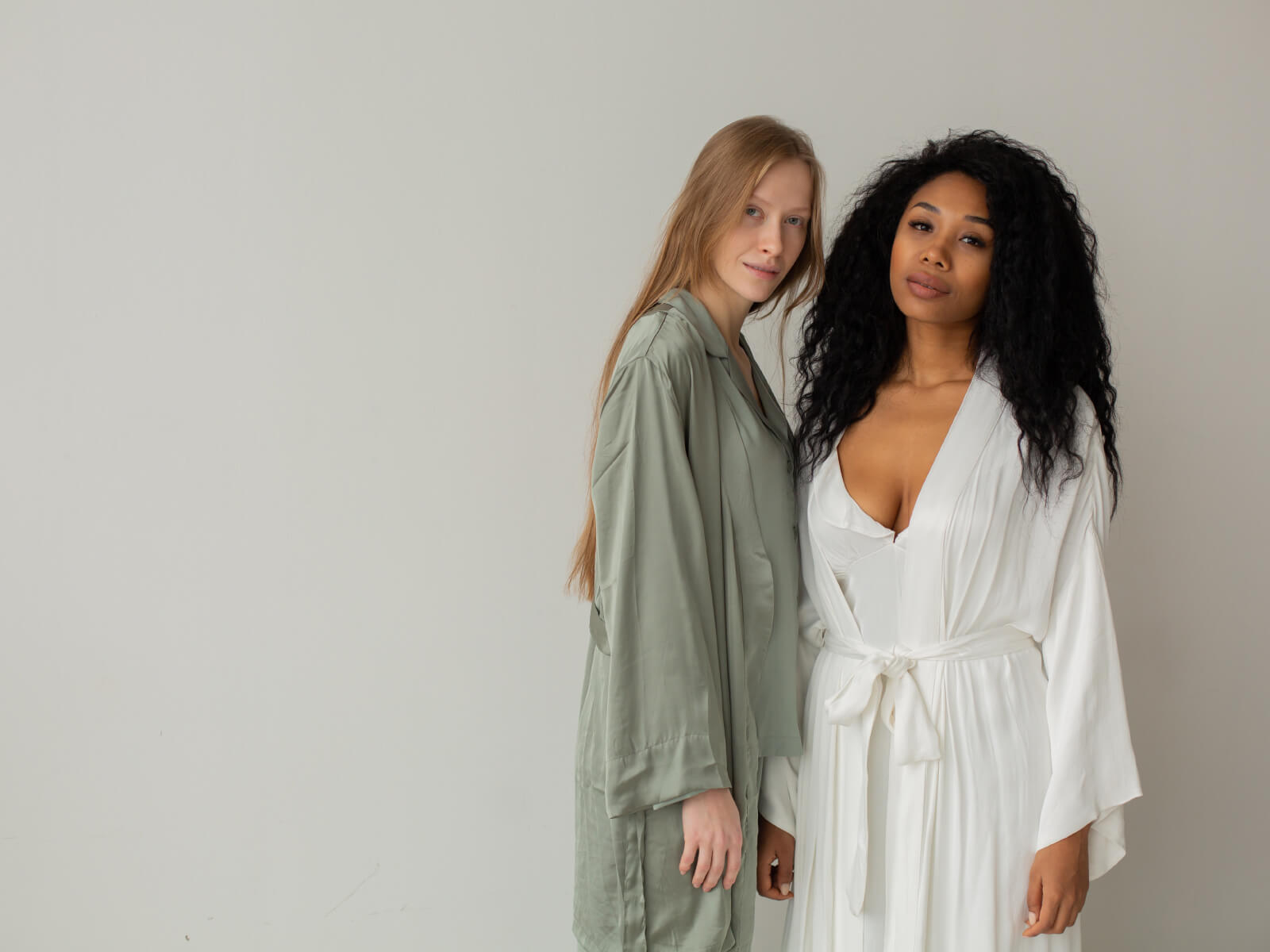Two women in white robes posing for a picture.