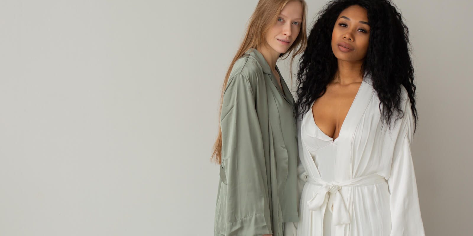 Two women in white robes posing for a picture.