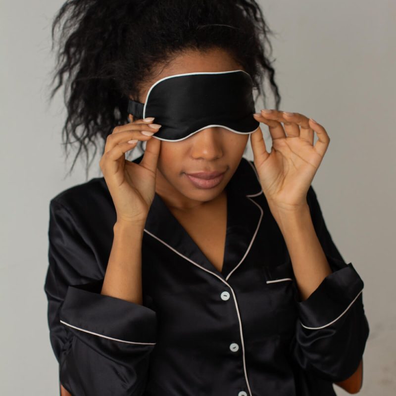 A woman in black pajamas holding onto some headphones